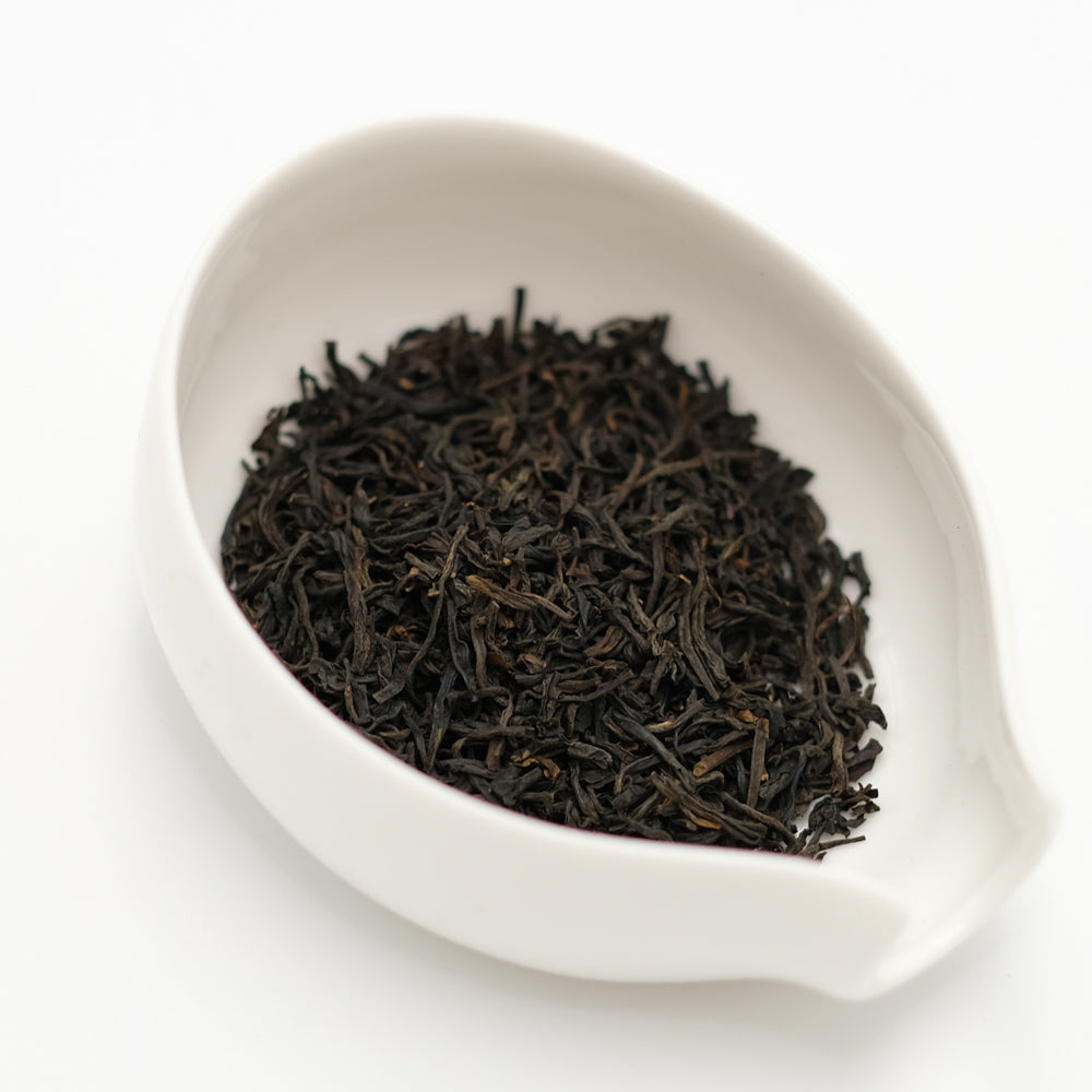 Tea Chapter Keemun red tea, dark twisted leaves with golden tips in a white porcelain scoop